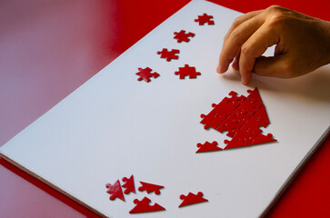 Hands assembling a red heart puzzle, symbolizing love, connection, and togetherness, perfect for romantic Valentine's Day or relationship-themed concepts.