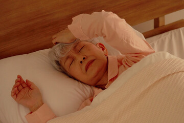 睡眠　うなされるシニア女性　ベッドルーム