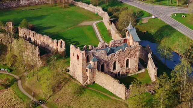 Dynamic aerial of historic stone medieval Dobele Castle, fresh green grass