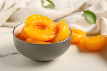 Bowl with sweet canned peaches on white background, closeup