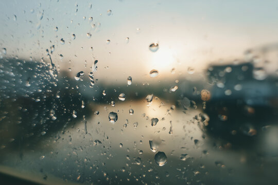 Close-up view of raindrops on a glass window with soft morning light and blurred city shapes in the background; atmospheric, emotional, minimalistic scene ideal for wellness, travel, mindfulness