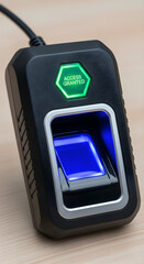 Modern biometric fingerprint scanner with green access granted light on wooden desk