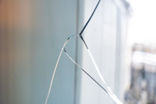 Large crack across a triple glazed window in a residential apartment. Indicates potential structural issues, thermal stress or manufacturing defect during construction.