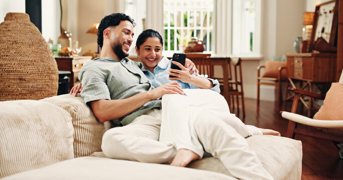 Couple, phone and relax on couch, laugh and scroll for funny video, bonding or post in living room at house. Happy woman, man and smartphone with mobile app, chat or meme on social media at apartment