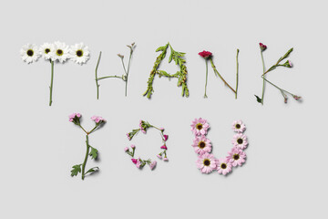 Text THANK YOU made of beautiful spring flowers on grey background