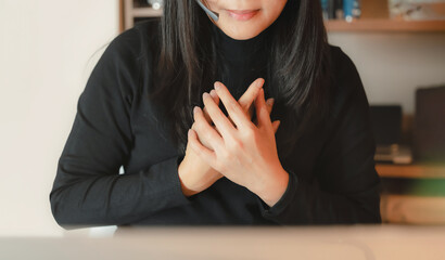 Close up of woman wearing headset placing hands on chest to express gratitude or empathy. Concept of customer service, emotional support, kindness, communication, and appreciation in business