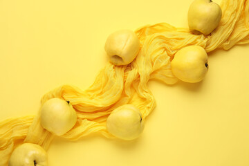 Composition with napkin and fresh quinces on yellow background