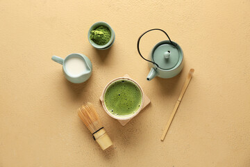 Composition with bowl of tasty matcha tea, chasen and teapot on beige grunge background