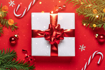 Christmas gift with red glitter decorations and Christmas tree branches on red background with...