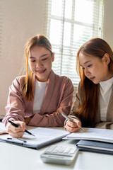 Obraz premium Businesswoman sitting at desk on couch in workplace or at home working on laptop and analyzing data on charts and graphs and writing on papers to make business plan and strategies for company, 