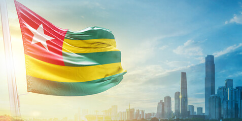 Togo flag wavering in beautiful clouds with building skyline. The flag with drone shot in beautiful...
