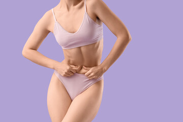 Young woman in underwear on lilac background. Liposuction concept
