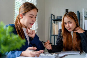 Businesswoman sitting at desk on couch in workplace or at home working on laptop and analyzing data on charts and graphs and writing on papers to make business plan and strategies for company, 