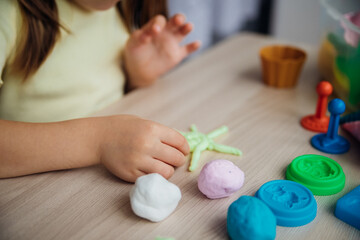 A little girl makes figurines out of colored airy plasticine, modeling dough. Hobbies for...