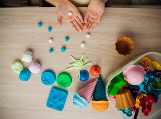 A little girl makes figurines out of colored airy plasticine, modeling dough. Hobbies for...