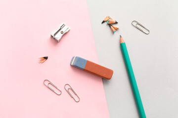 Eraser with sharpener, pencil and paper clips on color background