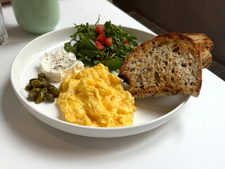 Scrambled Eggs, Butter, Capers, Salad and Rustic Bread. Outdoor Breakfast and Healthy Food Concept. Handheld Phone Photo, Selective Focus, No AI