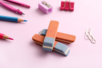 Erasers with stationery on lilac background