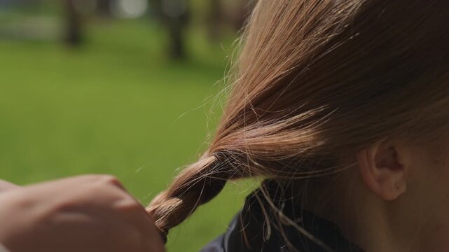 relaxed braid tutorial, careful hair braiding session conducted during peaceful sunlight hours, skilled fingers meticulously craft stylish side braid amidst bright daytime outdoor environment