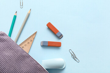 Erasers with pencil case and different stationery on blue background