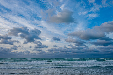 Waves crash on the shore under a cloudy sky at twilight on a beach