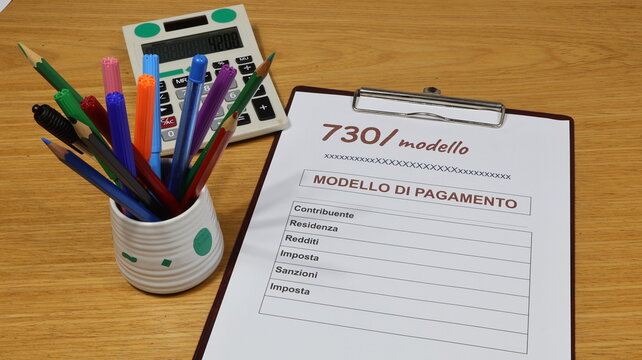 Filling out tax forms 730 in Italy, unified payment. Copy space for completing the 730 tax form. On the desk, stationery accessories include pens and a calculator.