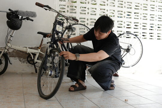Authentic young tomboy repairing a flat bicycle tire in a garage. Independent female mechanic fixing a bike wheel with tools. DIY maintenance and empowerment concept.