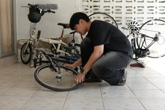 Authentic young tomboy repairing a flat bicycle tire in a garage. Independent female mechanic fixing a bike wheel with tools. DIY maintenance and empowerment concept.