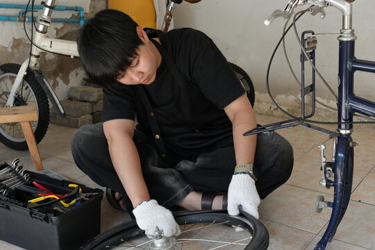 Authentic young tomboy repairing a flat bicycle tire in a garage. Independent female mechanic fixing a bike wheel with tools. DIY maintenance and empowerment concept.