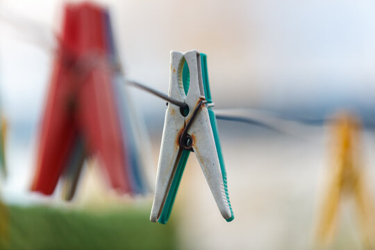 A green and white clothespin is hanging on a clothesline