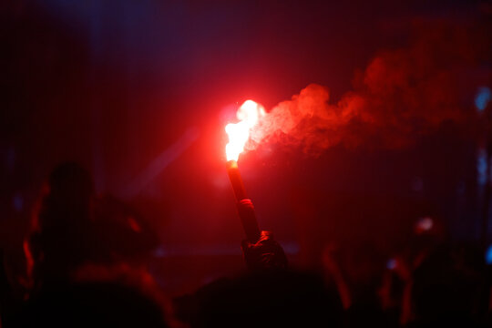 A person holding a red lit torch in a dark room