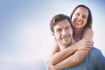 Obraz premium Portrait, love and couple with piggy back, vacation and bonding together. People, summer holiday and man carrying woman, sky and care with romance, marriage and happiness with space and date