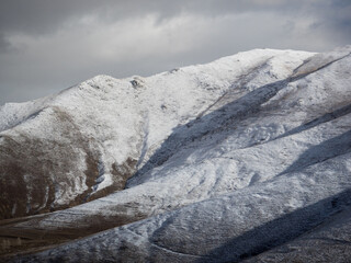 Landscape of snow-covered mountain peaks in winter with dramatic clouds