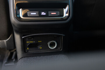 Air-condition panel in interior of a new car. Ports for the rear seats in a passenger car. Modern car 220v power socket for charging and accessories. 12v power socket inside car interior.