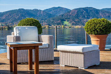 Relaxing seating arrangement by the calm lake with white chairs and a round pot in the morning sunlight