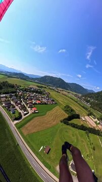 Aerial view person parachuting over green landscape houses river lake scenic nature adventure sky outdoor activity travel