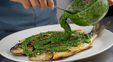 Plating grilled whole fish with vibrant green herb sauce