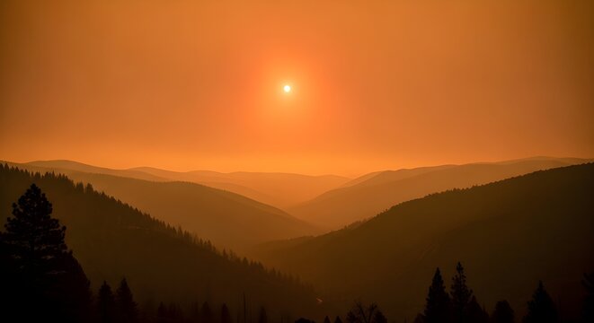 Orange sky with a bright sun over a valley filled with layers of dark silhouetted mountain ridges and tall evergreen trees