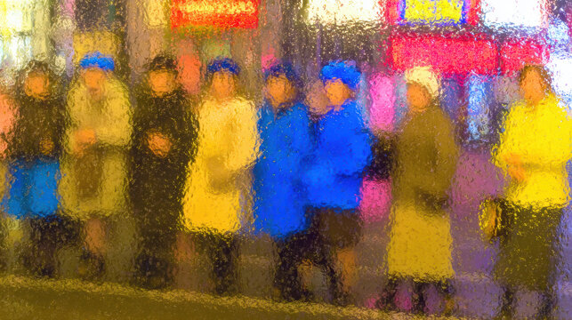 Blurred commuters waiting at urban bus stop at night with colorful lights and rain soaked glass