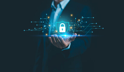 A businessman holding a glowing digital shield with lock icon and circuit lines, symbolizing cybersecurity, data protection, secure network infrastructure and advanced technology in modern business.