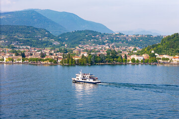 Passenger ferry cruising to Garda town on Garda lake, aerial drone view. Public transit on Garda lake