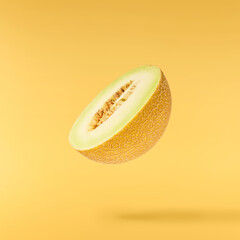 Fresh ripe Galia Melon falling in the air isolated on yellow background