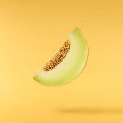 Fresh ripe Galia Melon falling in the air isolated on yellow background