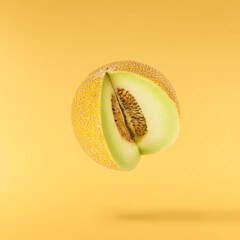 Fresh ripe Galia Melon falling in the air isolated on yellow background