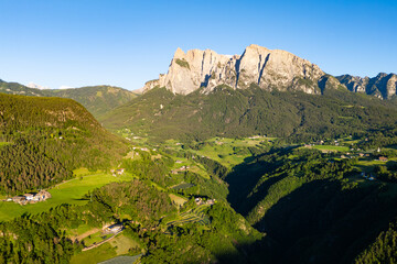 Dolomites farmland with mountain on skyline, aerial view. Sunset light in Dolomites, South Tyrol
