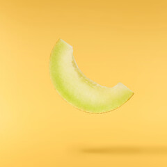 Fresh ripe Galia Melon falling in the air isolated on yellow background