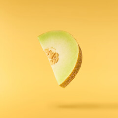 Fresh ripe Galia Melon falling in the air isolated on yellow background