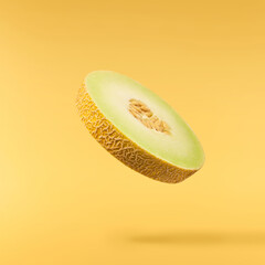 Fresh ripe Galia Melon falling in the air isolated on yellow background