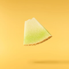 Fresh ripe Galia Melon falling in the air isolated on yellow background