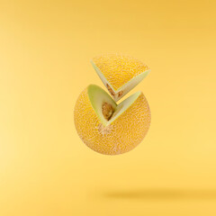Fresh ripe Galia Melon falling in the air isolated on yellow background